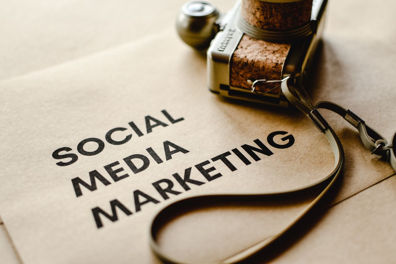 about-us-01 Close-up of a camera placed on brown paper with Social Media Marketing text, emphasizing digital marketing themes.